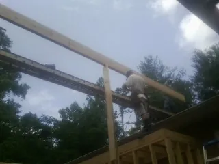 Carpenter setting a ridge beam over a new addition frame — Ice Dam Removal by Roofing Brothers in Pease