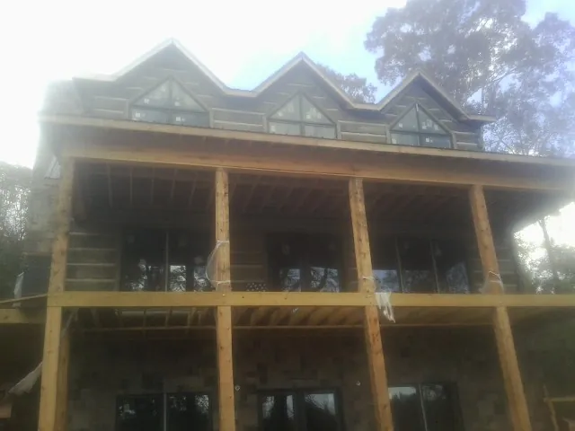 Dormers and porch framing on a large log home under construction — Roof Coating work by our crew in Pease
