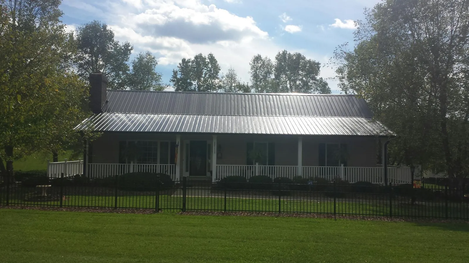 Gray metal roof on a brick ranch with a full width front porch — Gutter Guard Installation work by our crew in Pease