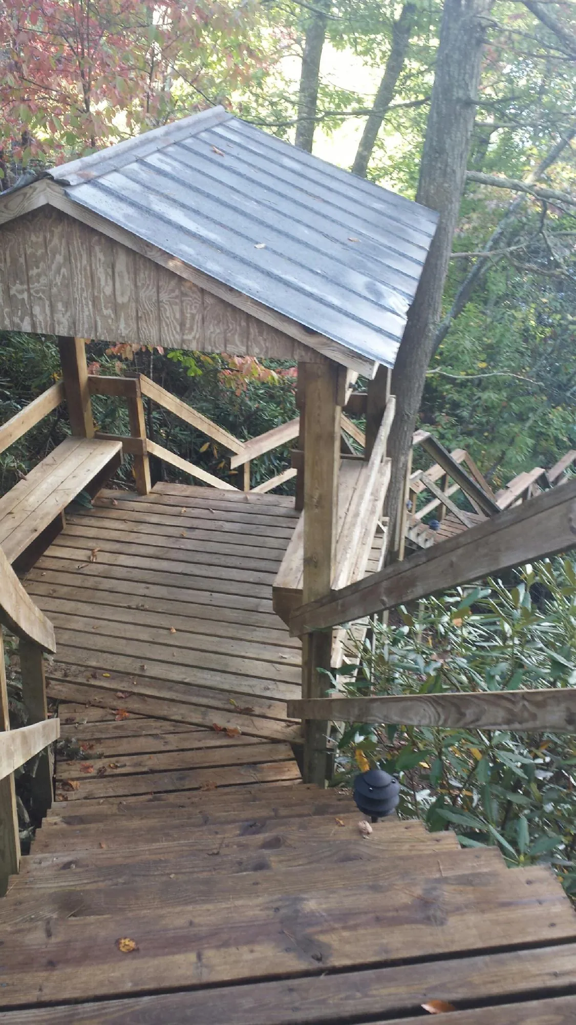 Metal roofed shelter over wooden steps on a wooded walkway — Skylight Repair & Installation work by our crew in Pease