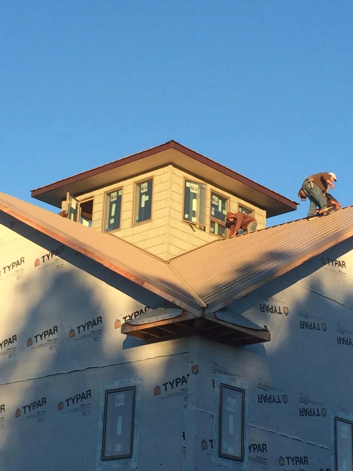 Roofers working around a rooftop cupola on a new metal roof at sunset — Roof Waterproofing in Pease by Roofing Brothers